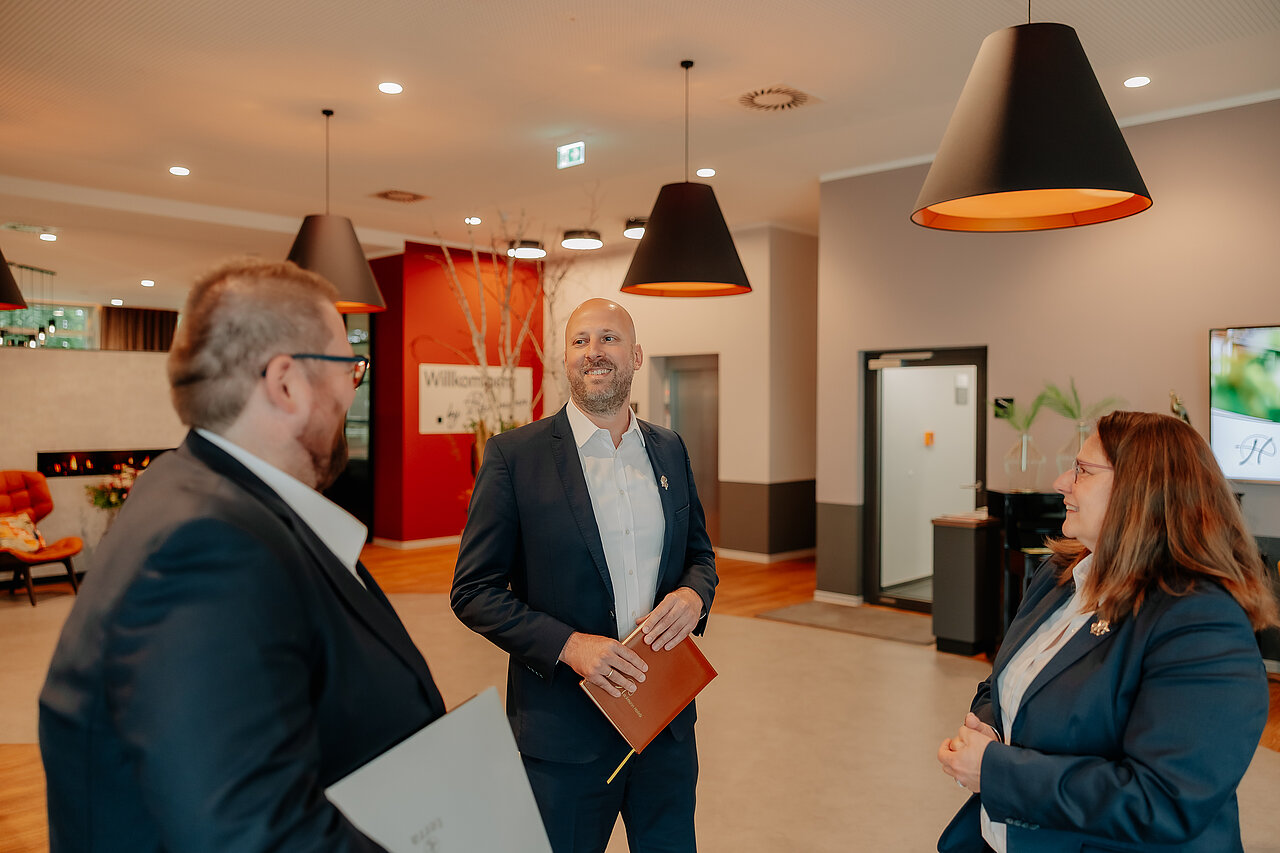 Mitarbeitende im Austausch in der Lobby des VIA PLAZA Meppen Drei Hotelmitarbeiter im Gespräch in der Lobby des VIA PLAZA Meppen