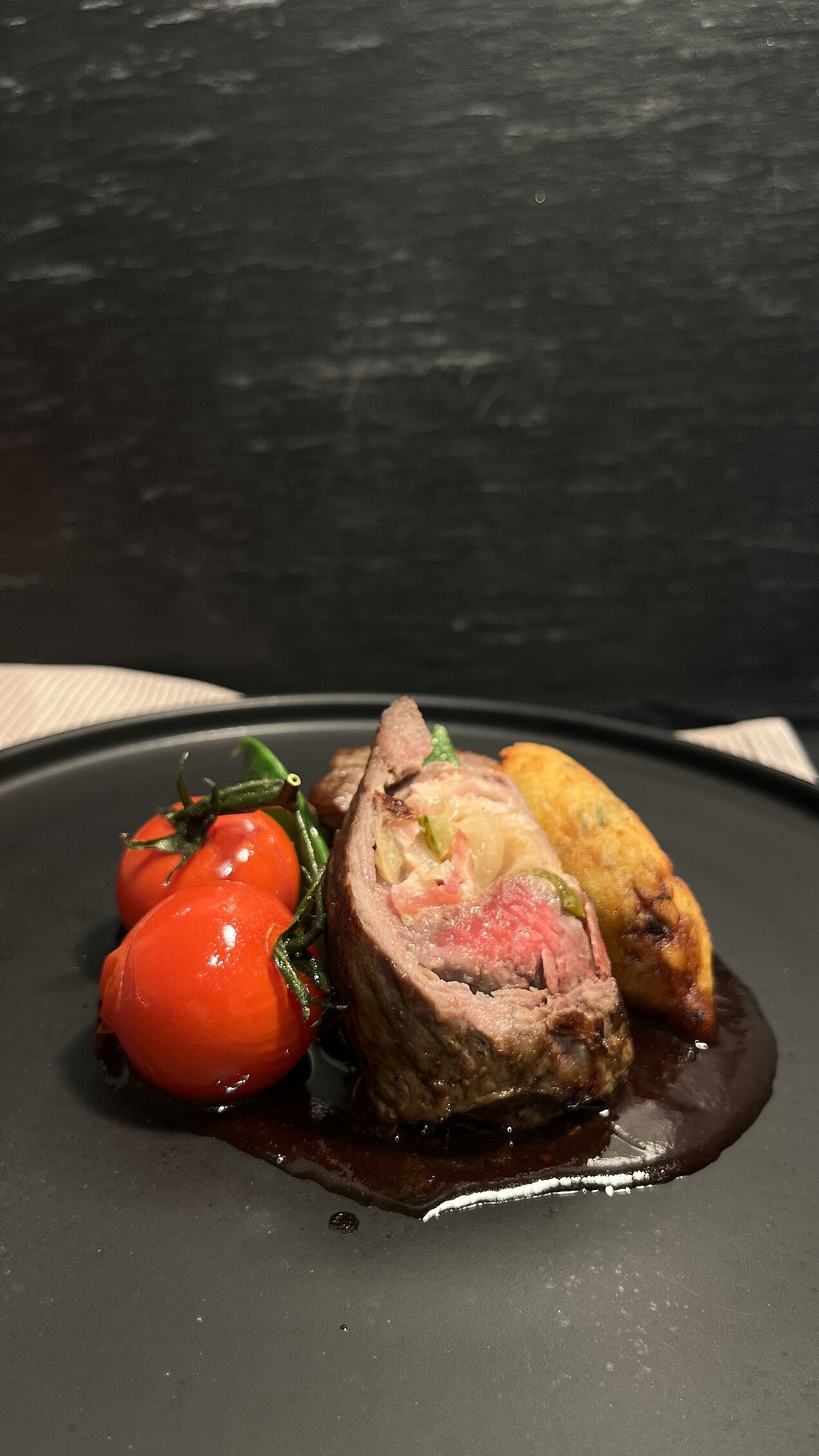 Rumpsteak-Roulade mit Portwein-Schalotten-Jus Klassisch gefüllte Rumpsteak-Roulade mit Portwein-Schalotten-Jus, Röstzwiebeln, Zuckerschoten, Kirschtomaten und Dauphine-Kartoffeln.