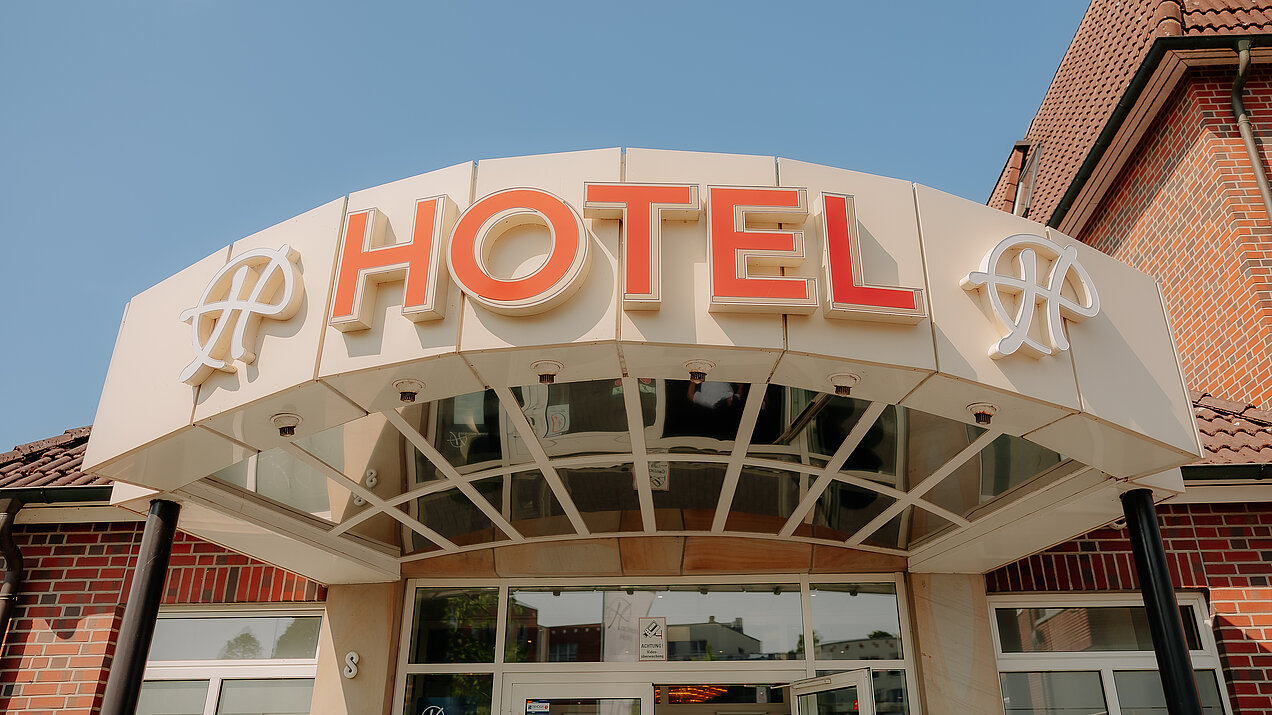 CASCADA Hotel Rheine – Hoteleingang mit Hackmann Hotels Logo Hoteleingang des CASCADA Hotel Rheine mit leuchtenden Hackmann Hotels "H"