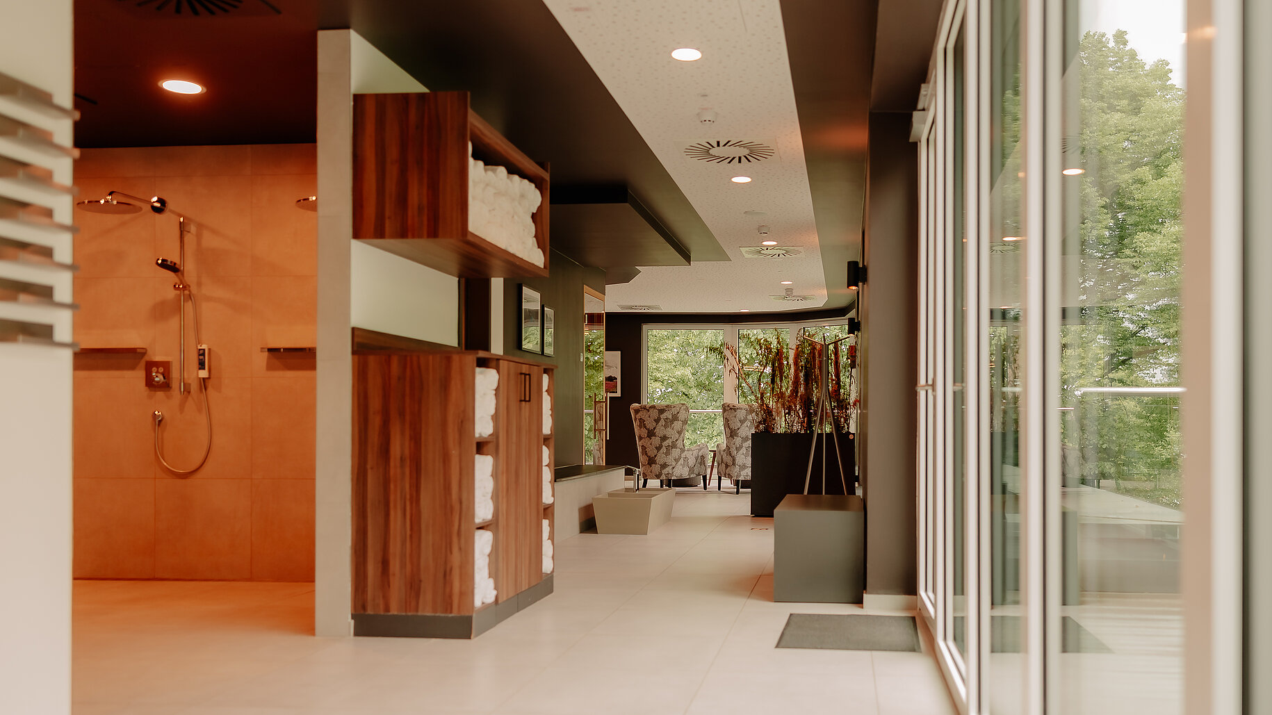 Wellnessbereich im VIA PLAZA Meppen mit Duschen und Handtuchstation Lichtdurchfluteter Gang im Wellnessbereich mit Duschen und Handtüchern
