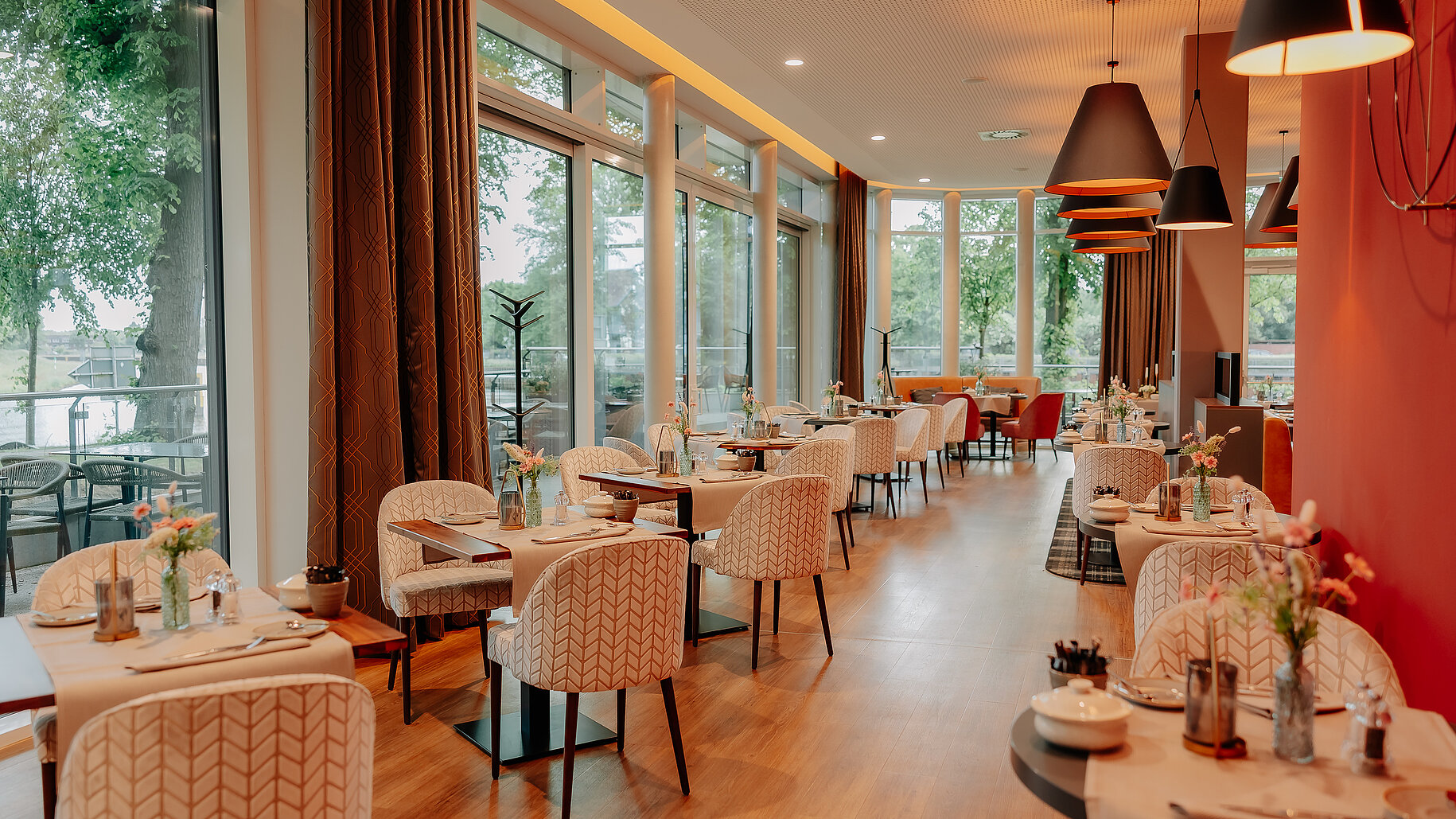 Restaurant mit Blick auf Terrasse und Ems Restaurantbereich im VIA PLAZA Meppen mit großen Panoramafenstern und gedeckten Tischen