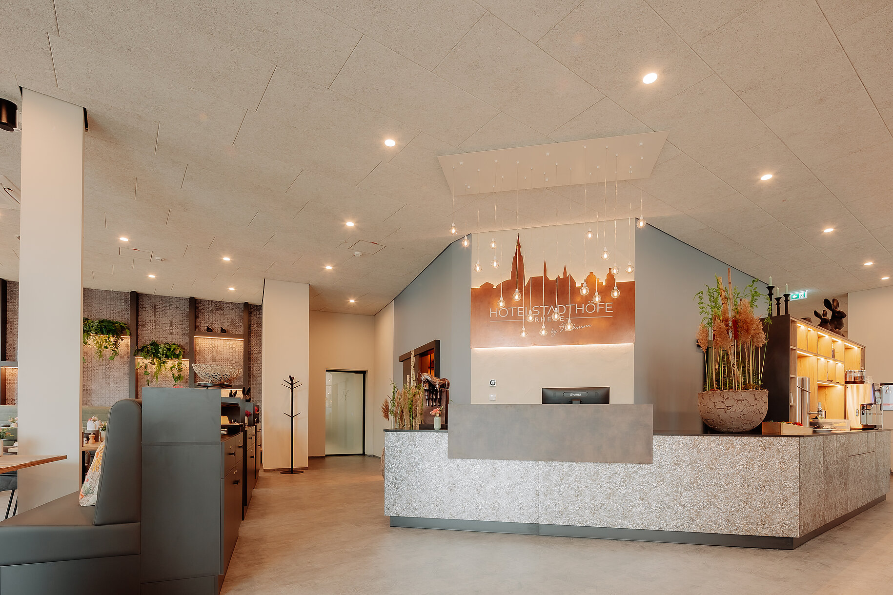 Rezeption im Hotel Stadthöfe Rhede Moderne Rezeption im Hotel Stadthöfe Rhede mit beleuchtetem Stadt-Silhouettenlogo