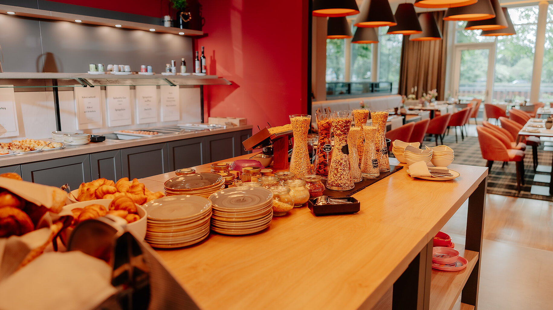 Frühstücksbereich mit Müsli- und Brotauswahl Frühstücksbuffet mit Müslibar, Croissants und warmen Speisen im modern gestalteten Restaurantbereich
