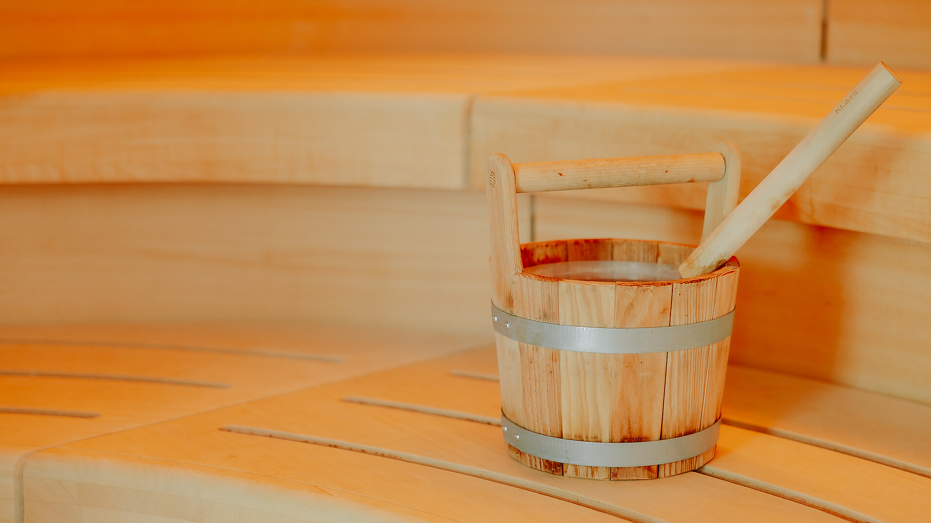 Detailaufnahme Saunaeimer in der finnischen Sauna im VIA PLAZA Klassischer Saunaeimer aus Holz auf Bank in der finnischen Sauna