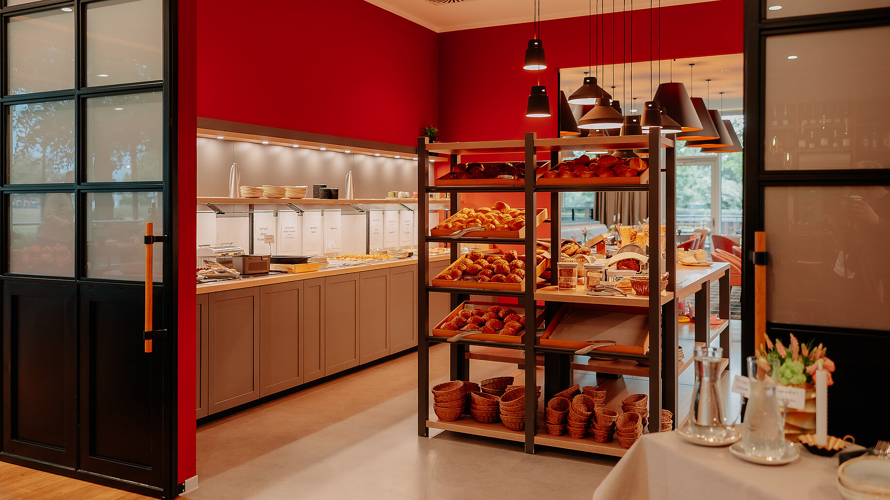 Frühstücksbereich mit Brötchenauswahl Reichhaltige Brötchenauswahl und Frühstücksbuffet in einem stilvoll eingerichteten Raum mit roten Wänden