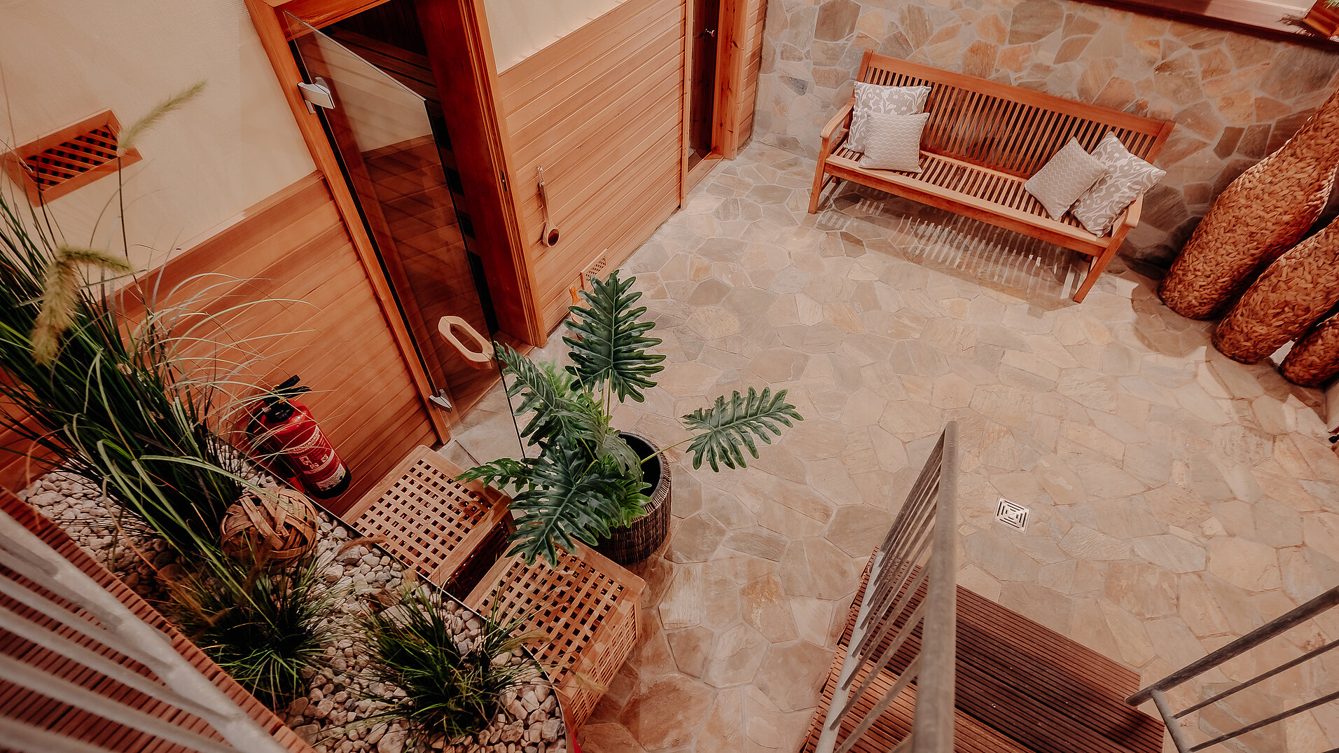 Saunabereich mit Naturstein und Sitzbank Blick von oben auf den Saunabereich im INSIDE Hotel Nordhorn mit Sitzbank und Pflanzen