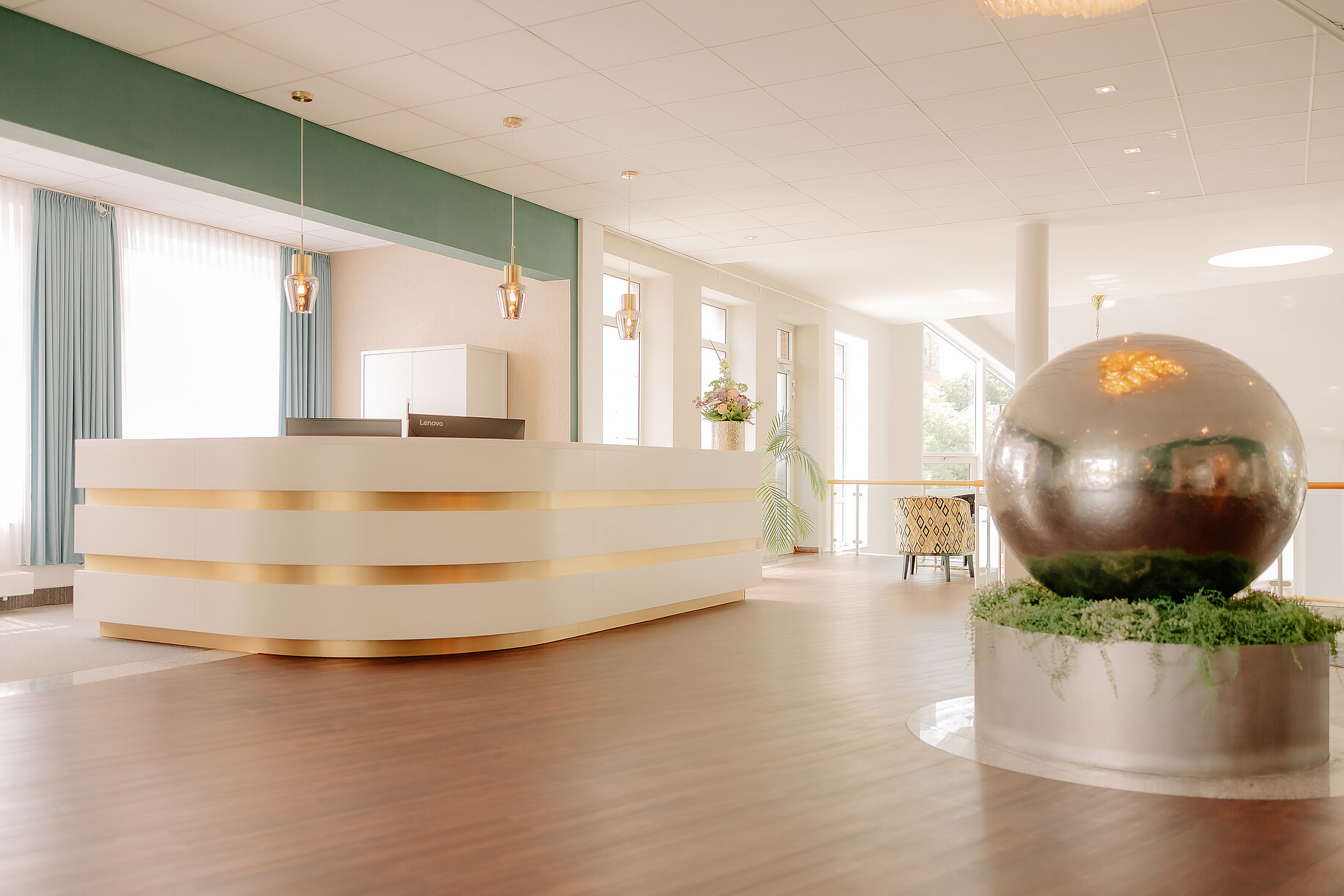 Empfangsbereich im CASCADA Hotel Rheine Helle Rezeption mit goldenen Akzenten in der Lobby des CASCADA Hotels Rheine