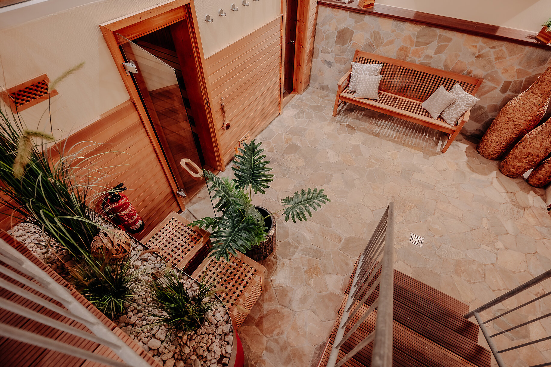 Saunabereich mit Naturstein und Sitzbank Blick von oben auf den Saunabereich im INSIDE Hotel Nordhorn mit Sitzbank und Pflanzen