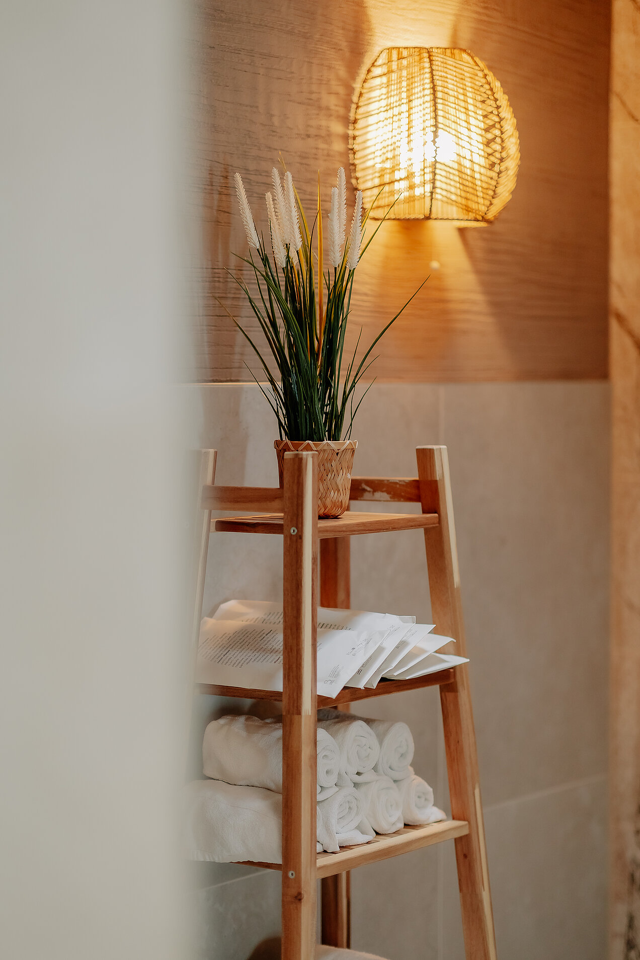 Handtuchregal im Ruhebereich Regal mit Handtüchern und Pflanze unter Wandleuchte im Ruhebereich