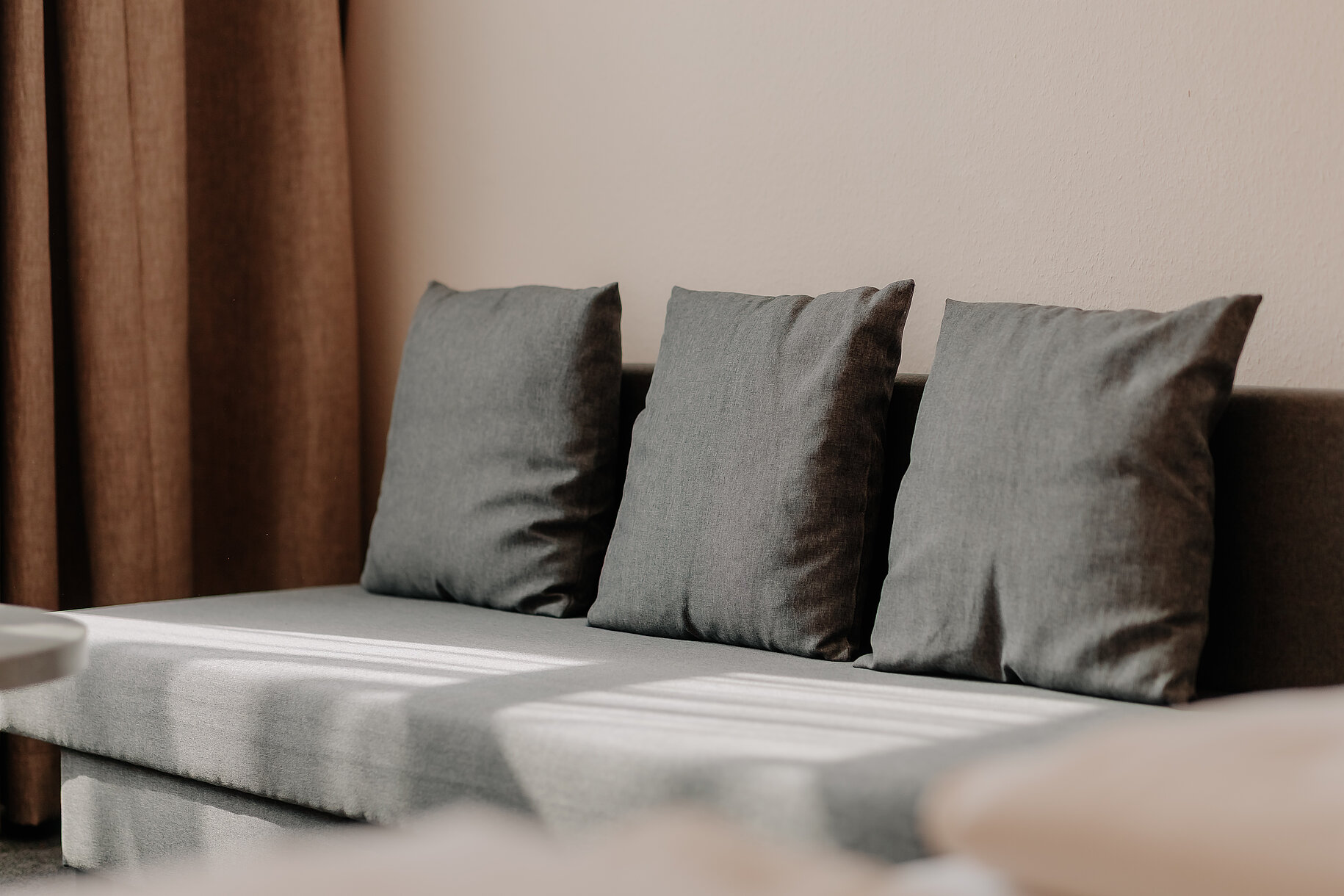 Sitzbereich im Hotelzimmer Graues Sofa mit Kissen im Hotelzimmer des Parkhotels Lingen