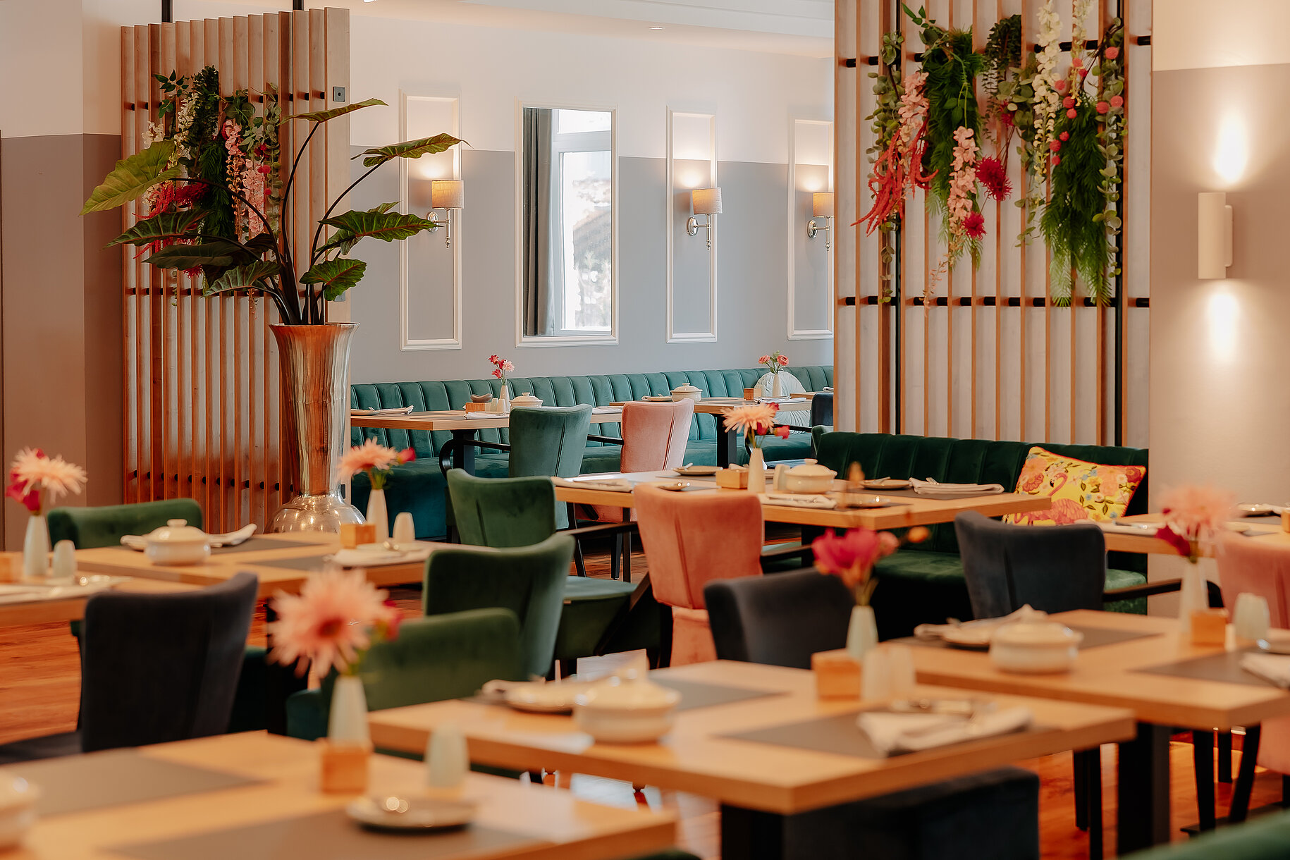 Frühstücksbereich im Stadthotel Borken Heller und stilvoll dekorierter Frühstücksraum mit bunten Polsterstühlen und floralen Akzenten im Stadthotel Borken