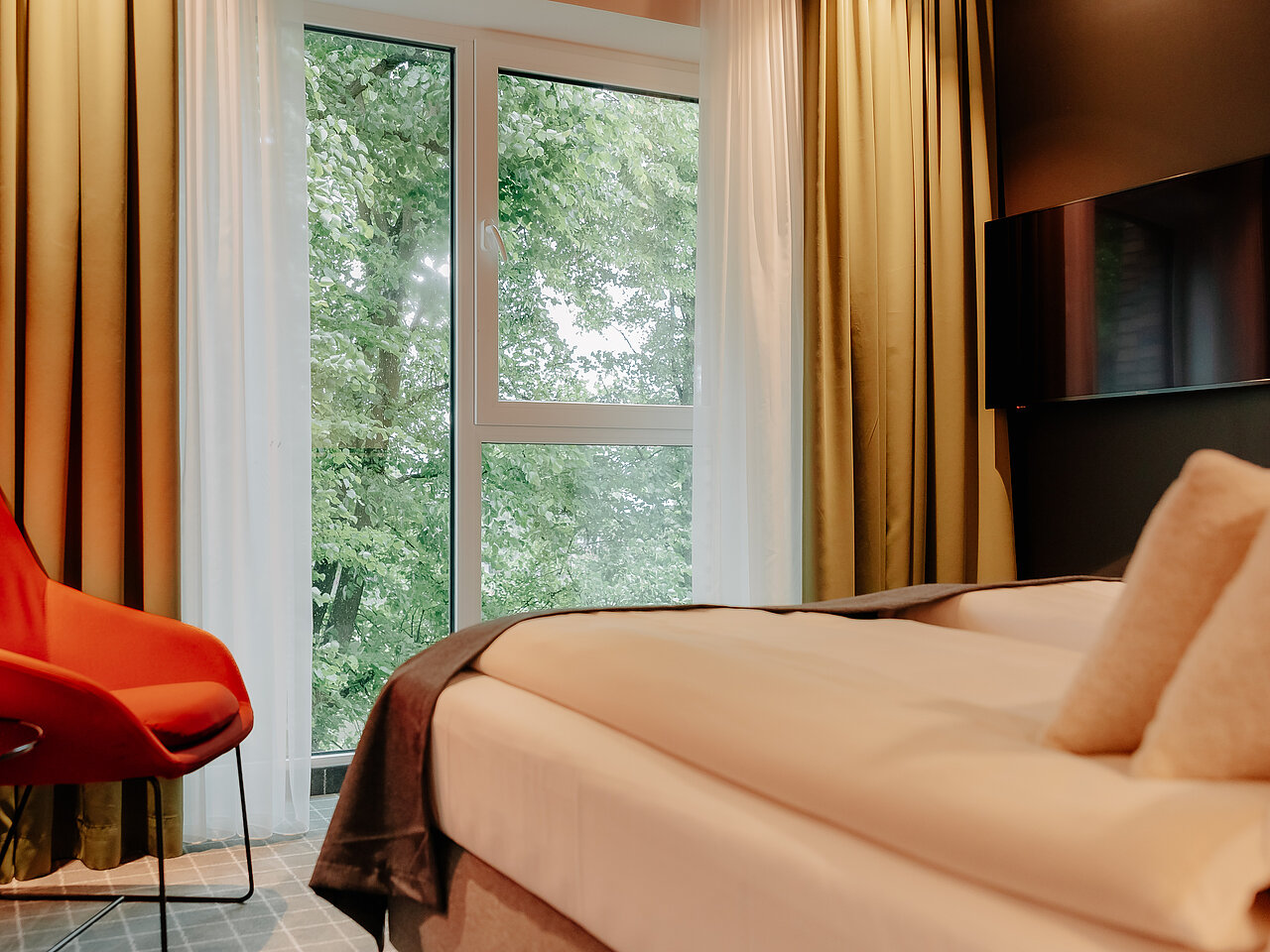 Doppelzimmer Superior mit Flussblick im VIA PLAZA Hotel Meppen Doppelzimmer mit stilvoller Einrichtung und Fensterblick auf grüne Baumkronen