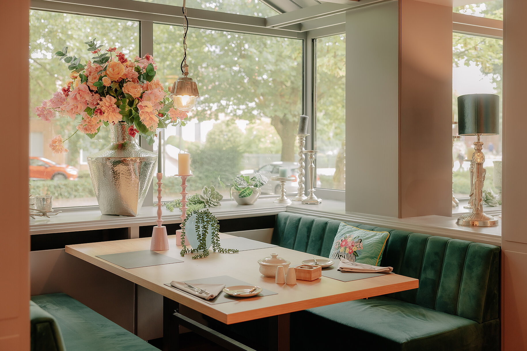 Fensterplatz mit Dekoration im Restaurant des Stadthotels Borken Fensterplatz im Restaurant des Stadthotels Borken mit grünem Samtpolster, Blumenarrangement und stimmiger Dekoration