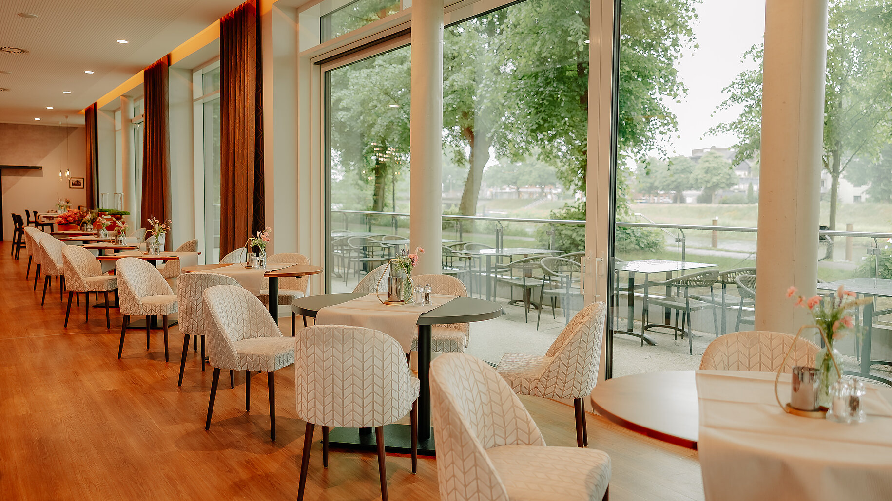 Heller Restaurantbereich mit Zugang zur Terrasse Gedeckte Tische im Restaurant des VIA PLAZA mit Blick auf die Außenterrasse