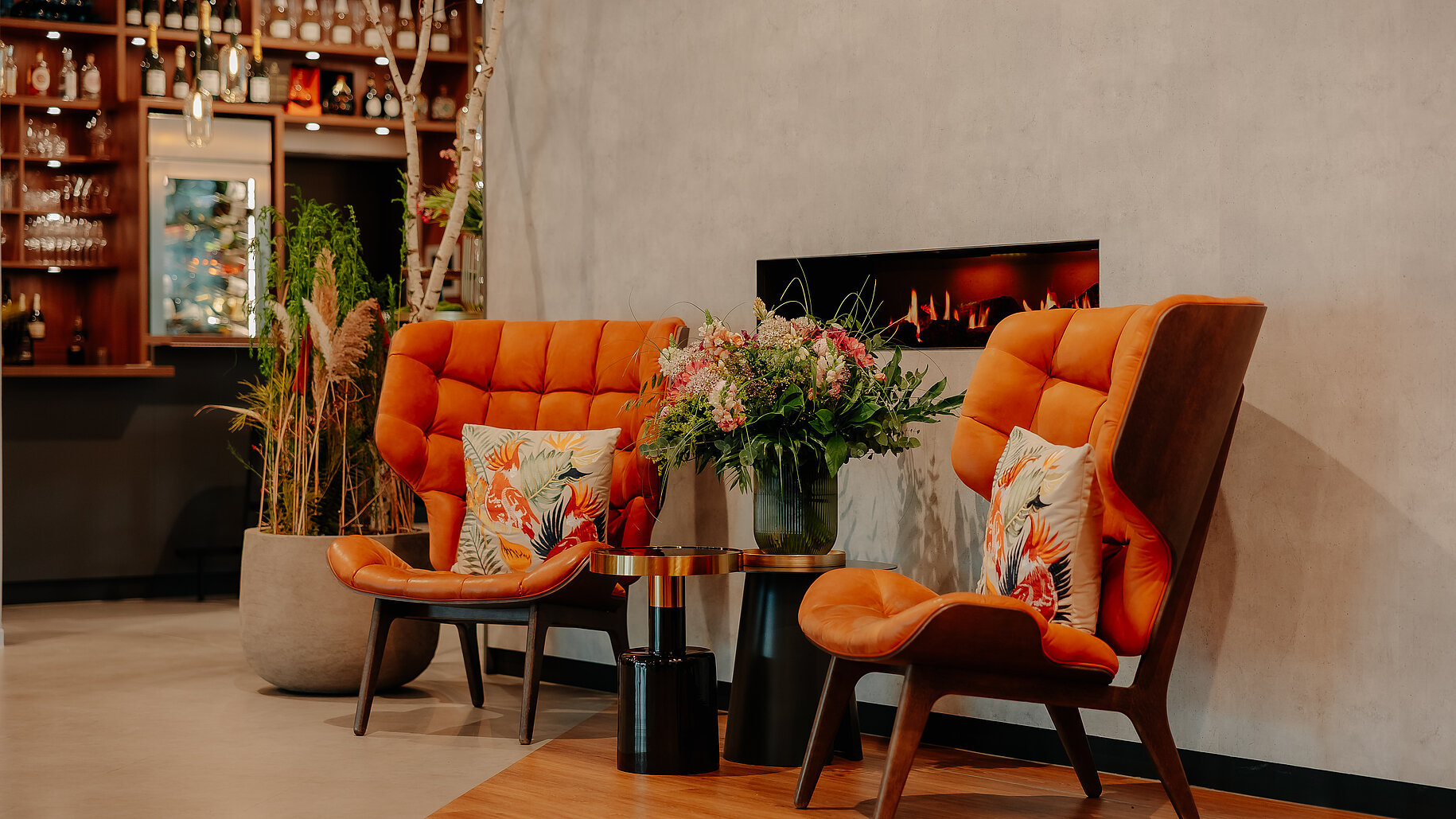 Sitzlounge mit Kamin und Blick zur Bar Gemütlicher Kaminbereich im VIA PLAZA Meppen mit Bar im Hintergrund